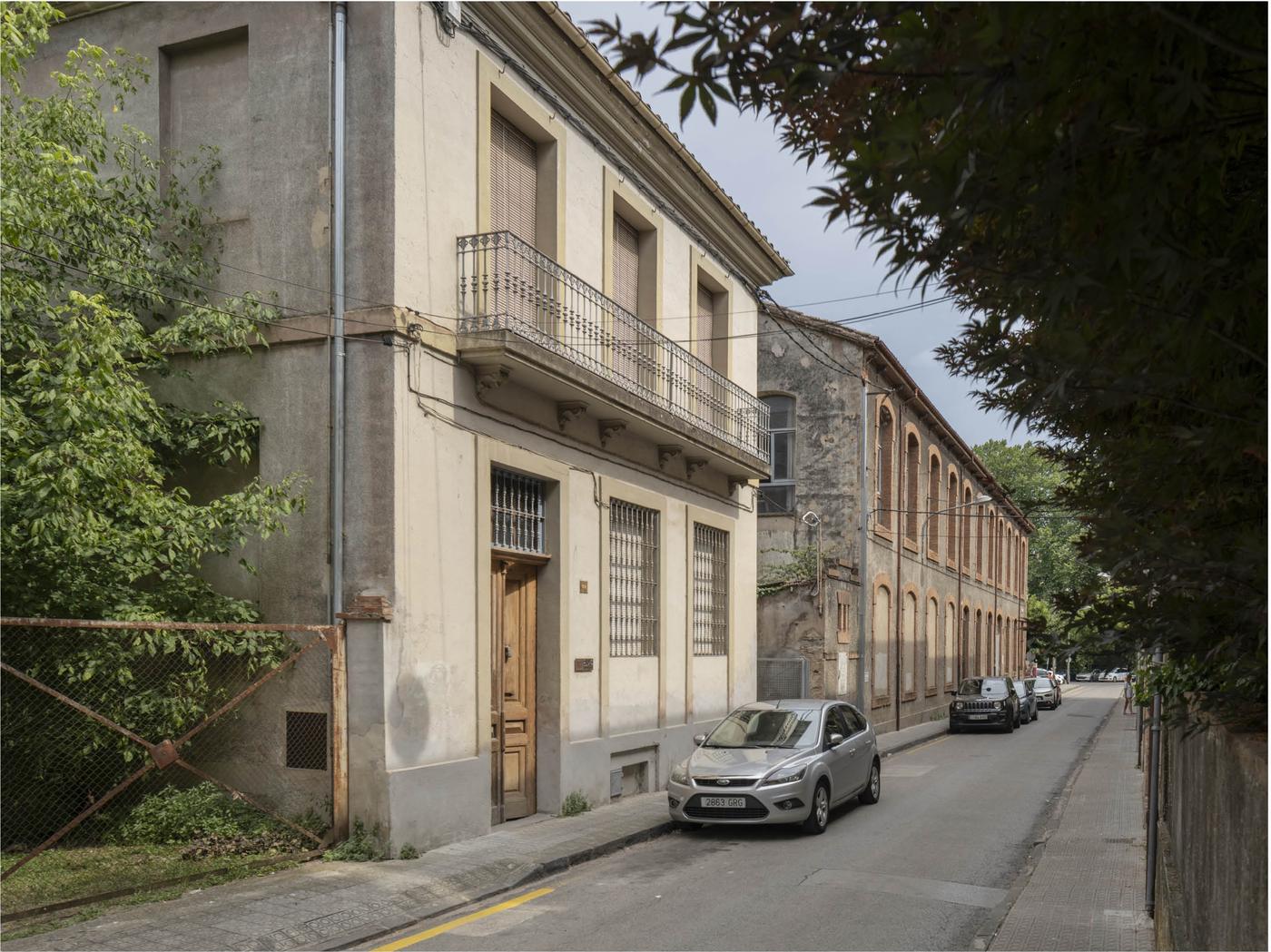 Casa con balcón junto a una nave de arcos